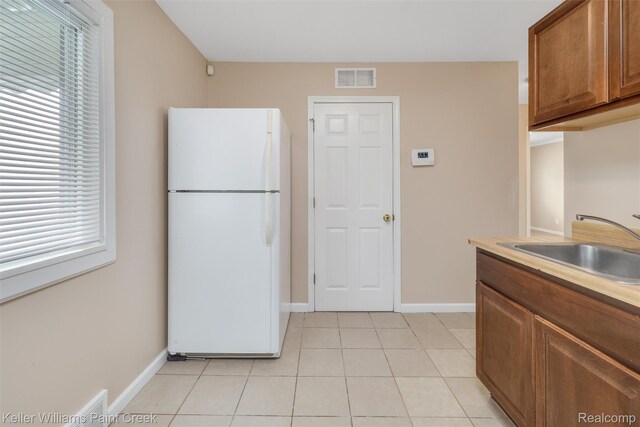 12777 Sherman Ave, Warren, MI 48089 - kitchen with freestanding refrigerator, a sink, brown cabinetry, baseboards, and light tile patterned floors