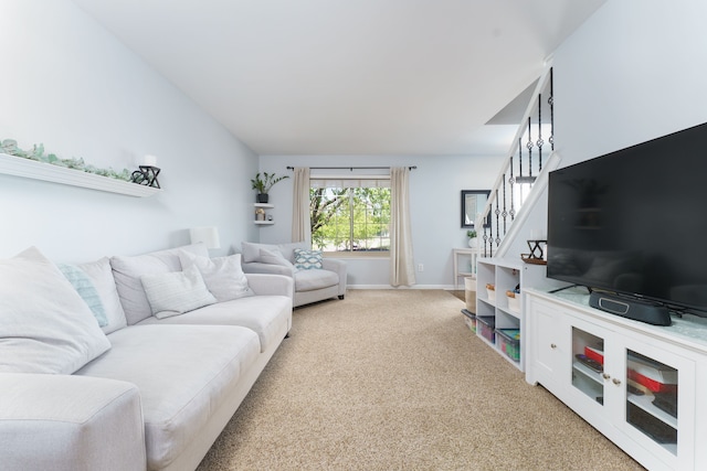 living area with light carpet, stairs, and baseboards