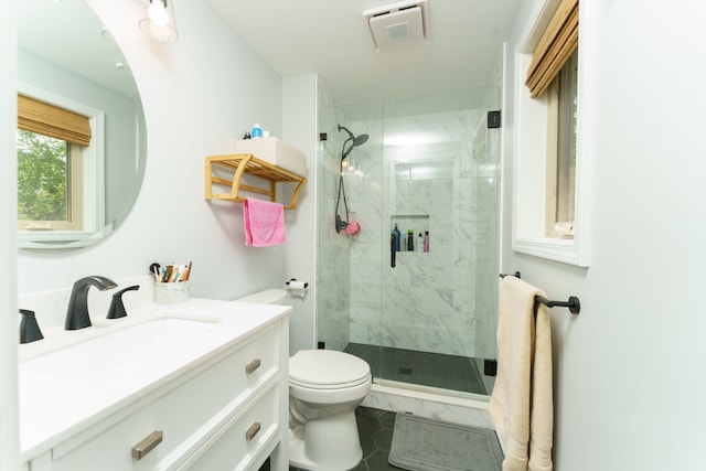 bathroom with a shower stall, toilet, vanity, and tile patterned floors