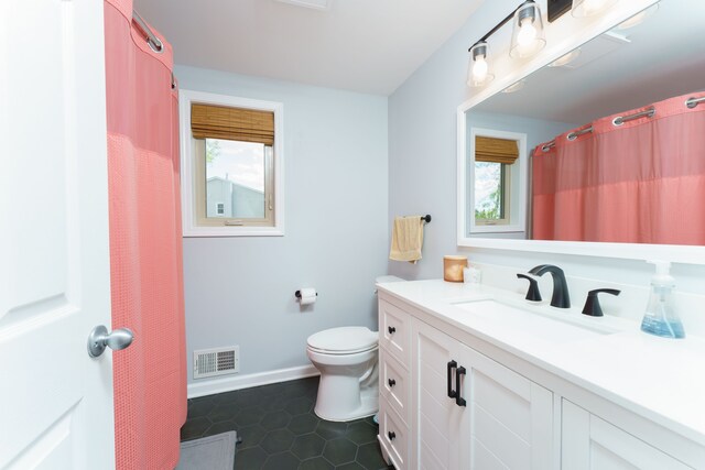 full bathroom featuring healthy amount of natural light, toilet, vanity, and tile patterned floors