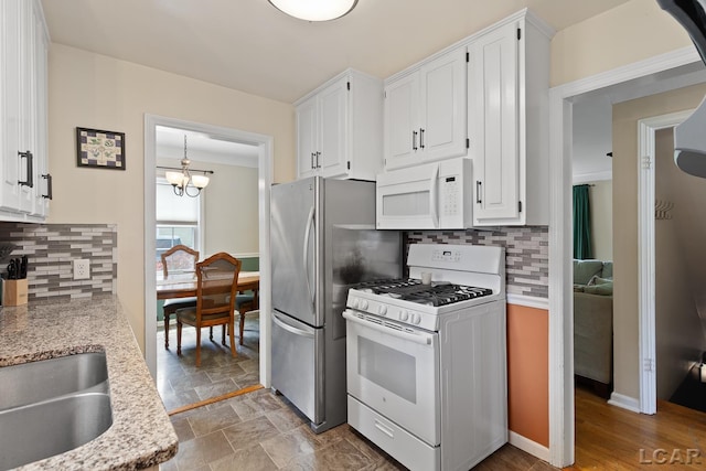 2369 Airport Rd, Adrian, MI 49221 - kitchen featuring white appliances, white cabinets, decorative backsplash, and a chandelier