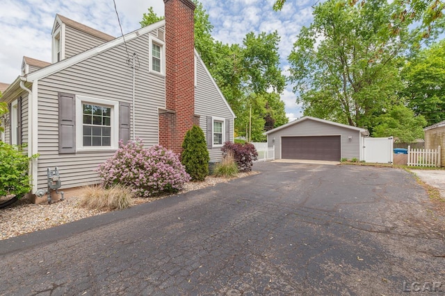 2369 Airport Rd, Adrian, MI 49221 - view of home's exterior featuring a detached garage, a chimney, fence, and an outdoor structure