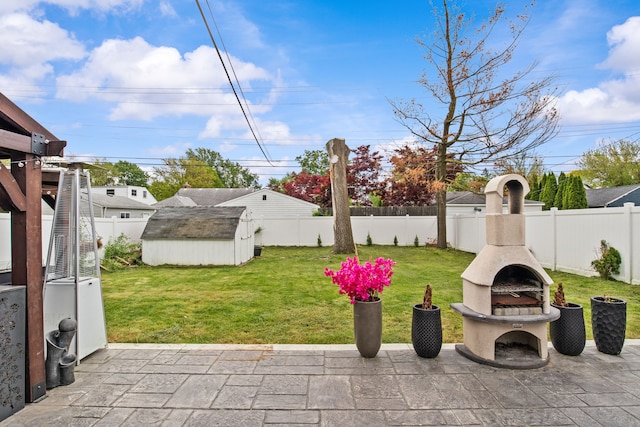 view of patio / terrace featuring exterior fireplace, a storage unit, and an outbuilding