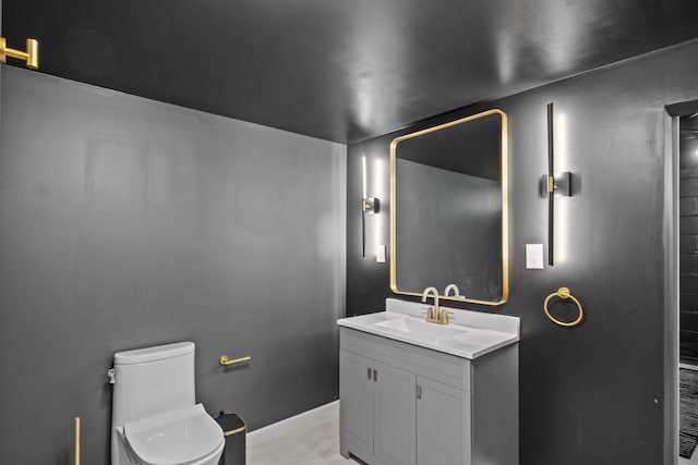 bathroom with toilet, vanity, and marble finish flooring