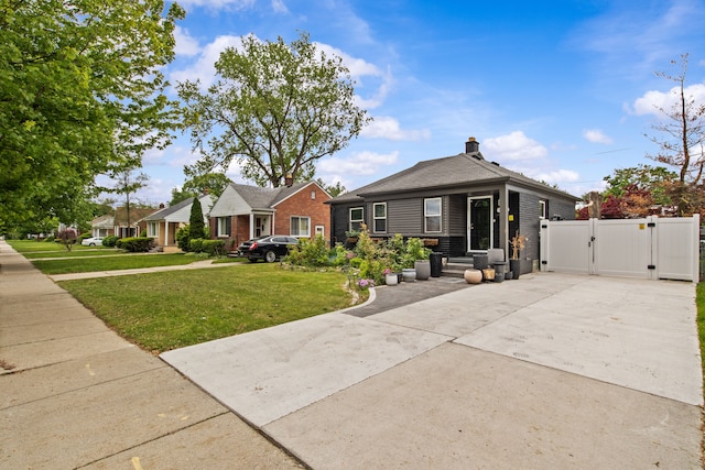 view of front of home featuring a gate, a front yard, and concrete driveway