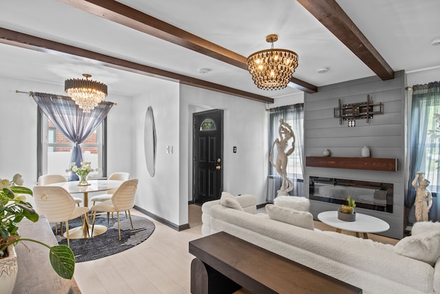 living area with a chandelier, beam ceiling, plenty of natural light, and a glass covered fireplace
