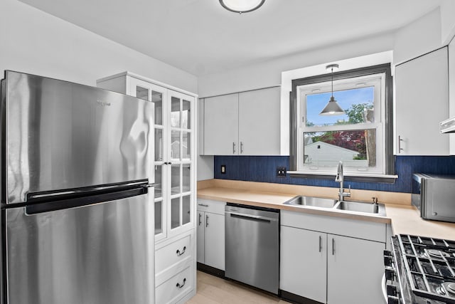 kitchen featuring appliances with stainless steel finishes, a sink, light countertops, and white cabinets