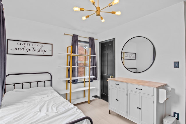 bedroom with a chandelier, light wood-type flooring, and baseboards