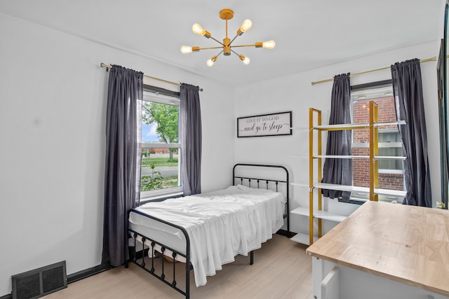 bedroom with a chandelier and light wood-style flooring