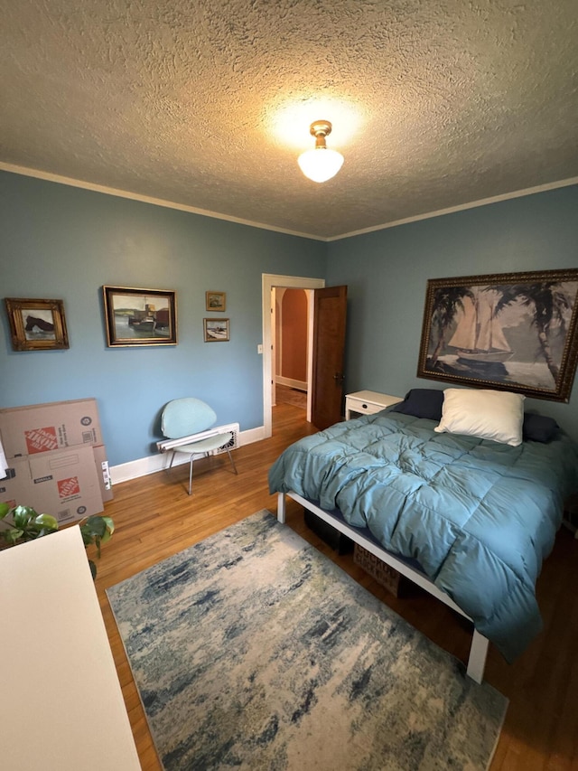 701 Chestnut St, Grayling, MI 49738 - bedroom with wood finished floors, a textured ceiling, ornamental molding, and baseboards