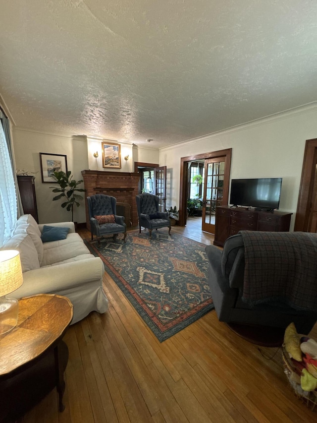 701 Chestnut St, Grayling, MI 49738 - living room featuring a textured ceiling, hardwood / wood-style floors, a brick fireplace, and crown molding