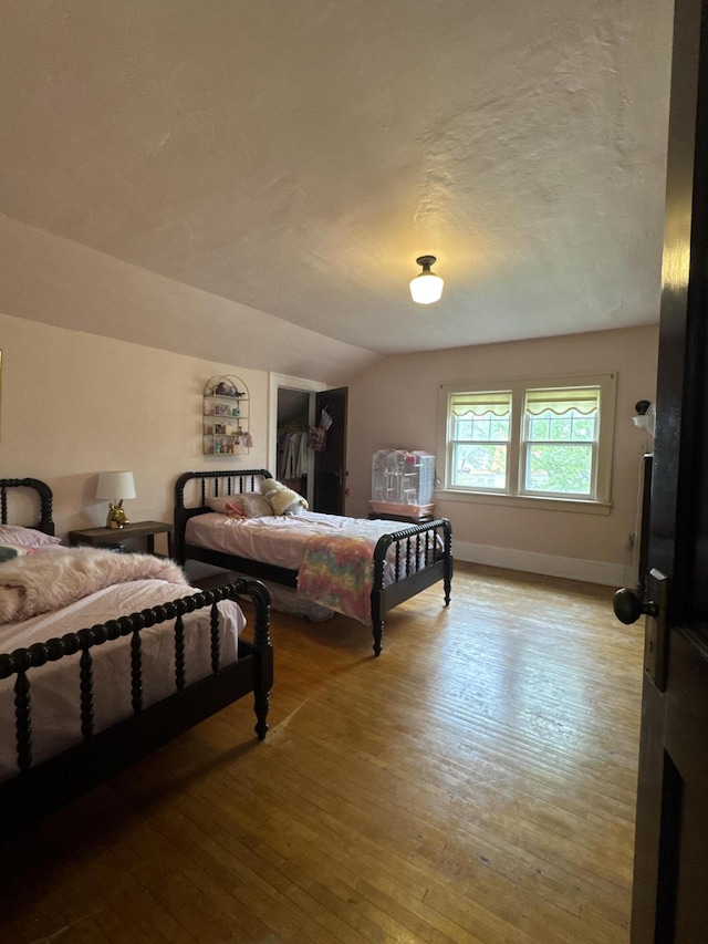 701 Chestnut St, Grayling, MI 49738 - bedroom with hardwood / wood-style flooring, baseboards, a textured ceiling, and vaulted ceiling