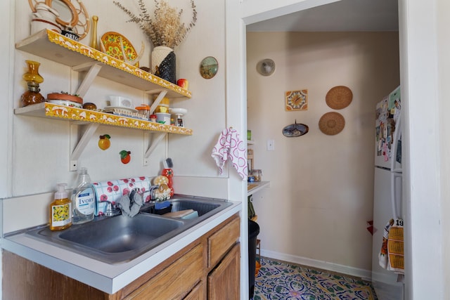 447 W Vine St, Kalamazoo, MI 49001 - kitchen with freestanding refrigerator, a sink, baseboards, brown cabinets, and open shelves
