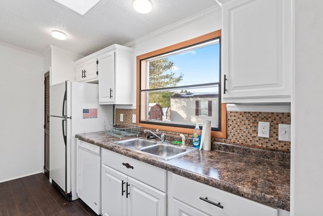 25 Hunters Rill, Lapeer, MI 48446 - kitchen featuring white appliances, a sink, dark countertops, crown molding, and decorative backsplash