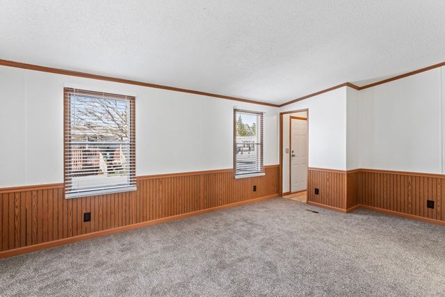 25 Hunters Rill, Lapeer, MI 48446 - carpeted empty room featuring wainscoting, crown molding, wooden walls, and a textured ceiling