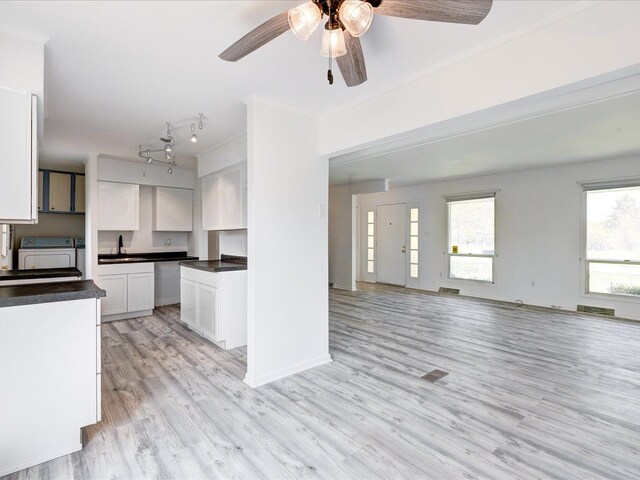 5943 Avalon Cir, Lexington, MI 48450 - kitchen with independent washer and dryer, a sink, dark countertops, white cabinetry, and light wood-type flooring