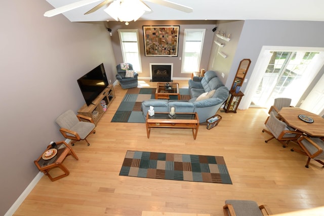 722 Bennington St, East Tawas, MI 48730 - living area with wood finished floors, a ceiling fan, baseboards, and a fireplace