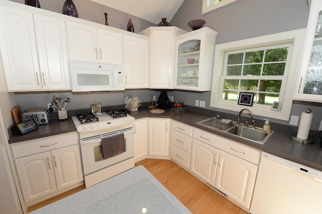 722 Bennington St, East Tawas, MI 48730 - kitchen with white appliances, dark countertops, a sink, and light wood-style floors