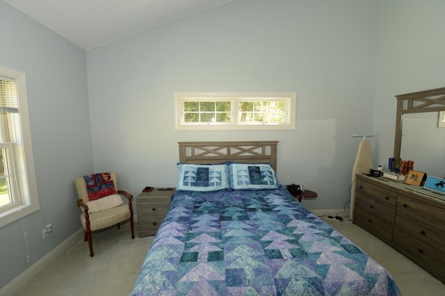 722 Bennington St, East Tawas, MI 48730 - bedroom with light colored carpet, vaulted ceiling, multiple windows, and baseboards