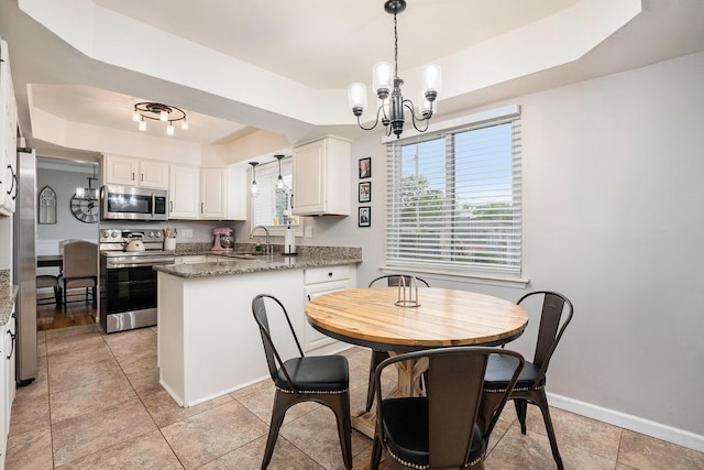 dining room with a raised ceiling, a chandelier, baseboards, and light tile patterned flooring