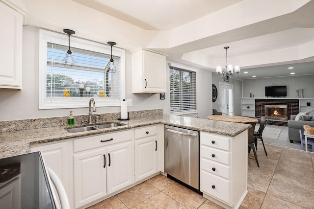 kitchen with a sink, dishwasher, range with electric cooktop, a tray ceiling, and a fireplace