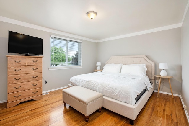 bedroom featuring baseboards, light wood-type flooring, and crown molding