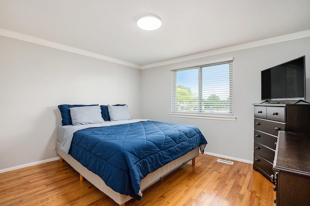 bedroom with baseboards, ornamental molding, and light wood finished floors