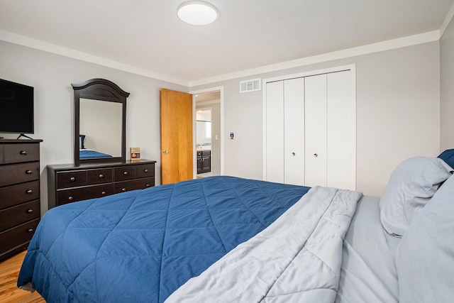 bedroom with wood finished floors, a closet, and crown molding