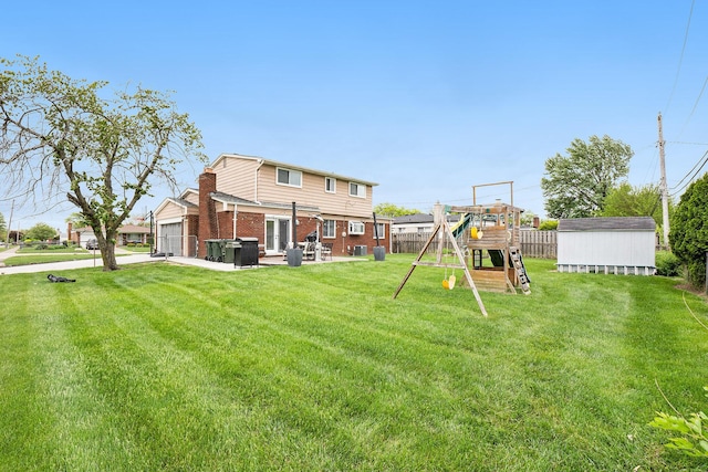 view of yard with a playground, a storage shed, an attached garage, an outdoor structure, and a patio area