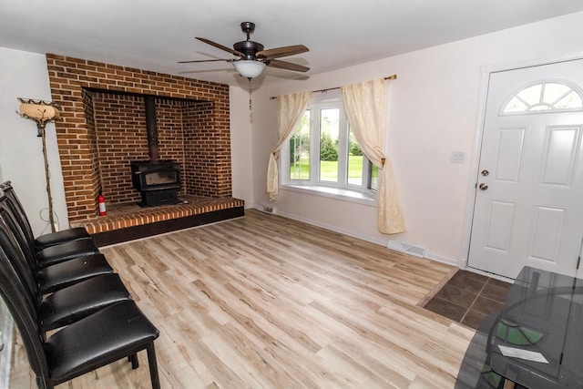 789 W Castle Rd, Fostoria, MI 48435 - unfurnished living room featuring a wood stove, ceiling fan, wood finished floors, and baseboards