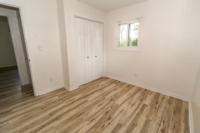 789 W Castle Rd, Fostoria, MI 48435 - unfurnished bedroom featuring baseboards, light wood-type flooring, and a closet