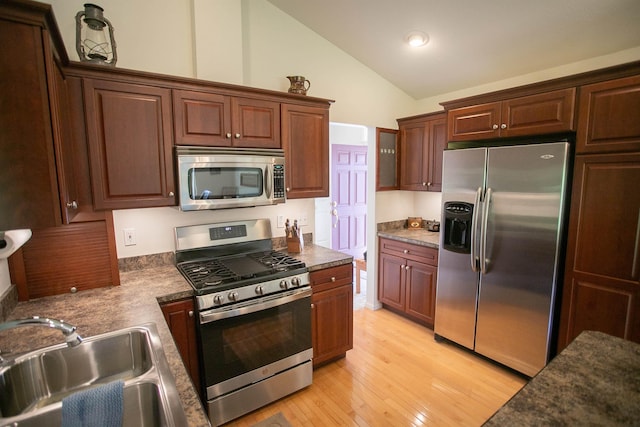 1820 Elk Ct, Owosso, MI 48867 - kitchen with stainless steel appliances, a sink, light wood finished floors, high vaulted ceiling, and dark countertops