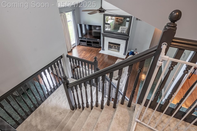 42739 Pond View Dr, Sterling Heights, MI 48314 - stairs featuring ceiling fan, a fireplace with flush hearth, and wood finished floors