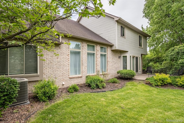 42739 Pond View Dr, Sterling Heights, MI 48314 - rear view of house with brick siding, a patio area, central AC, a yard, and a shingled roof