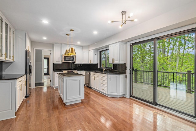 2315 Adare Rd, Ann Arbor, MI 48104 - kitchen with appliances with stainless steel finishes, a sink, a kitchen island, white cabinetry, and tasteful backsplash