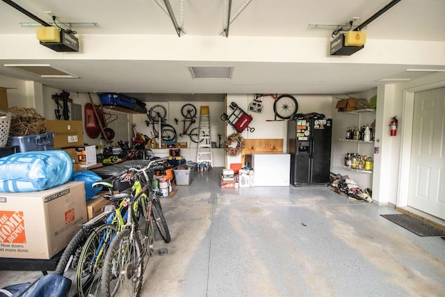 5221 Whittaker Trl, Linden, MI 48451 - garage featuring black refrigerator with ice dispenser, a garage door opener, and a workshop area