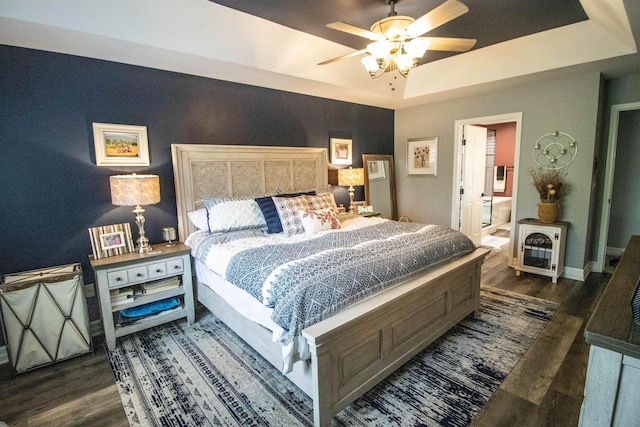 5221 Whittaker Trl, Linden, MI 48451 - bedroom with wood finished floors, a tray ceiling, baseboards, ceiling fan, and ensuite bathroom