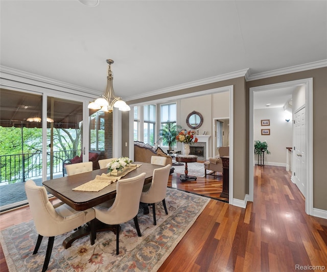 17747 Parkshore Dr, Northville, MI 48168 - dining area with ornamental molding, wood finished floors, a fireplace, a chandelier, and baseboards