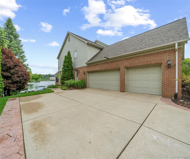 17747 Parkshore Dr, Northville, MI 48168 - view of home's exterior with brick siding, a shingled roof, concrete driveway, an attached garage, and a water view