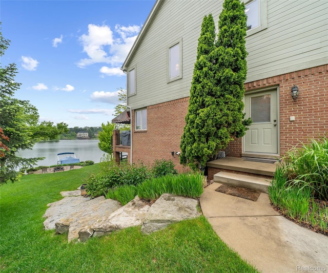 17747 Parkshore Dr, Northville, MI 48168 - doorway to property with brick siding, a lawn, and a water view