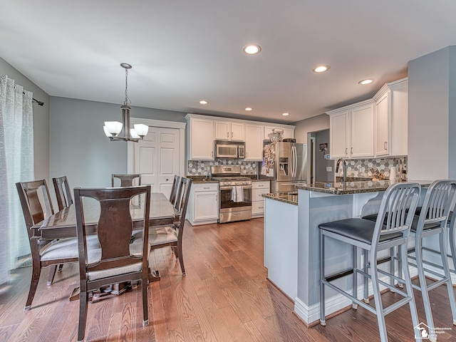 469 Corinth Cir, Dundee, MI 48131 - kitchen with stainless steel appliances, a chandelier, a peninsula, white cabinetry, and dark wood-style floors