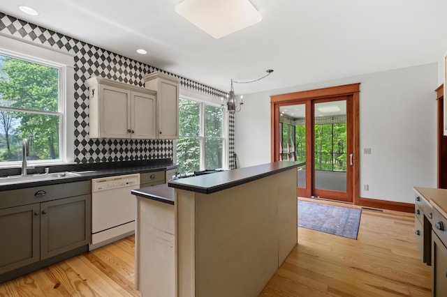 9934 W Fg Ave, Kalamazoo, MI 49009 - kitchen with white dishwasher, a sink, dark countertops, light wood-style floors, and a center island