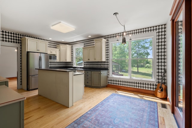 9934 W Fg Ave, Kalamazoo, MI 49009 - kitchen with stainless steel appliances, wallpapered walls, dark countertops, light wood finished floors, and a center island