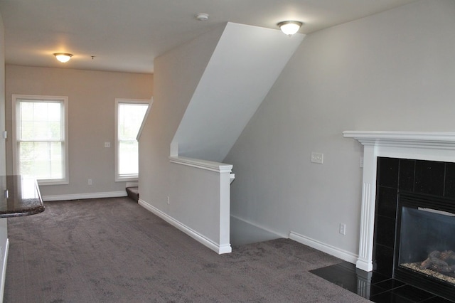 45862 S Stonewood Rd Unit 218, Canton, MI 48187 - unfurnished living room featuring a tiled fireplace, dark colored carpet, and baseboards