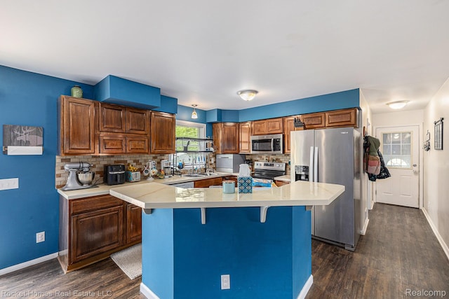 6621 Dove Rd, Kimball, MI 48074 - kitchen featuring stainless steel appliances, dark wood finished floors, a kitchen bar, tasteful backsplash, and light countertops
