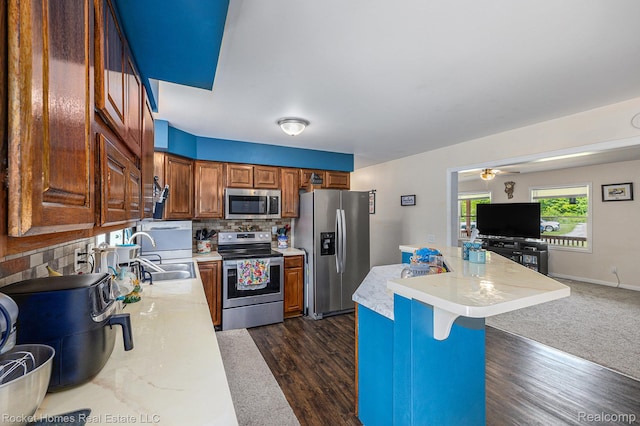 6621 Dove Rd, Kimball, MI 48074 - kitchen featuring appliances with stainless steel finishes, a sink, light countertops, tasteful backsplash, and a kitchen bar