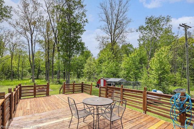 6621 Dove Rd, Kimball, MI 48074 - wooden deck with outdoor dining space, a view of trees, a yard, and an outdoor structure