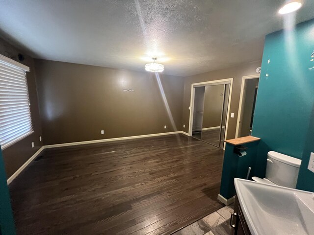 72 E Brink St, Grant, MI 49327 - empty room featuring wood finished floors, baseboards, a sink, and a textured ceiling