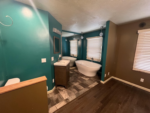72 E Brink St, Grant, MI 49327 - full bath featuring a textured ceiling, wood finished floors, vanity, a freestanding tub, and baseboards
