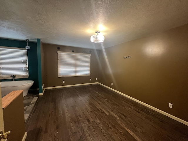 72 E Brink St, Grant, MI 49327 - unfurnished room featuring dark wood-style floors, a textured ceiling, baseboards, and a chandelier